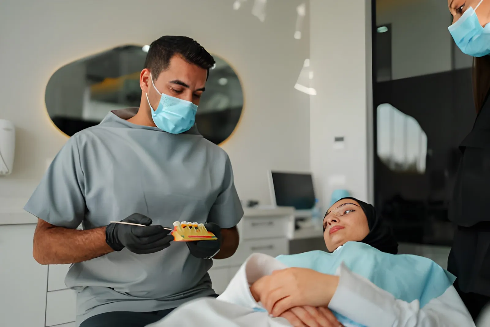 Dental professional holding a clear 3D-printed surgical guide for dental implants with precision metal drill sleeves visible.